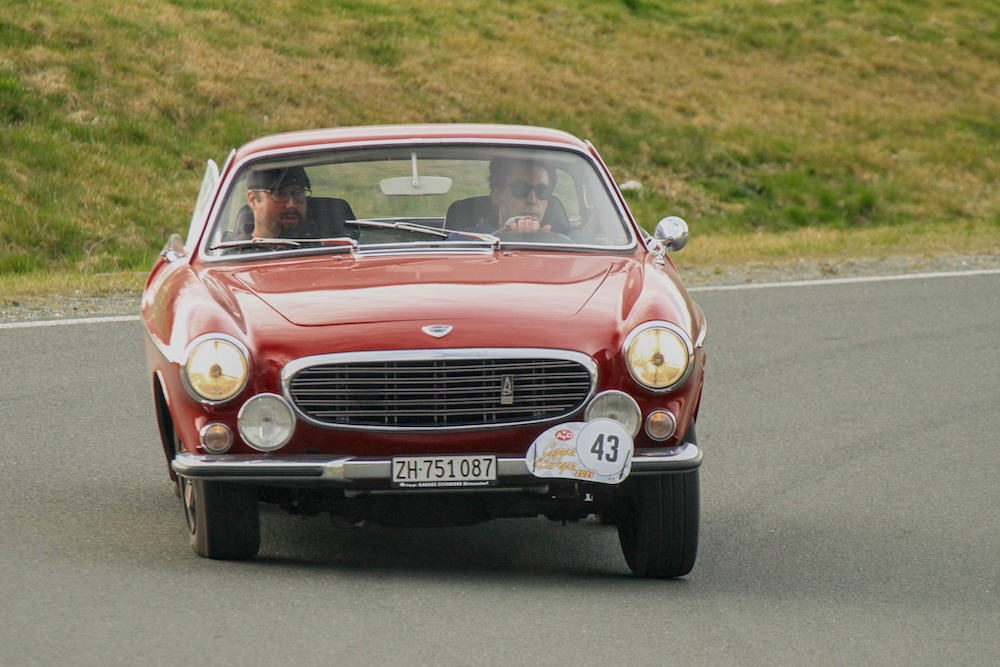 A red Volvo 1800E coming round a bend at high speed