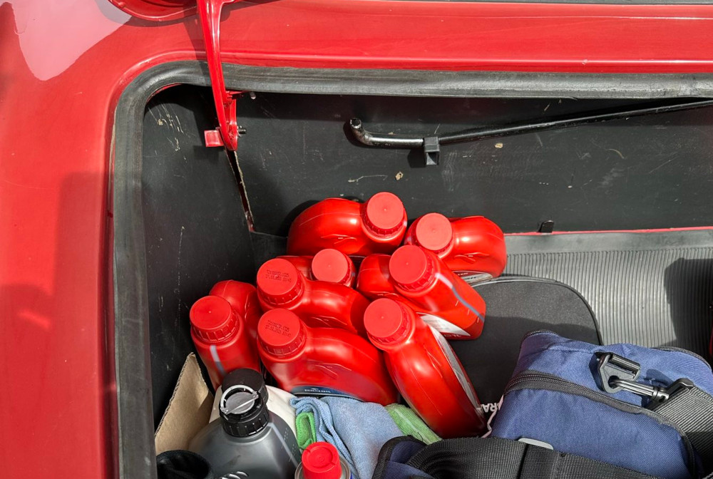 Eight red 1 litre oil bottles in a car boot
